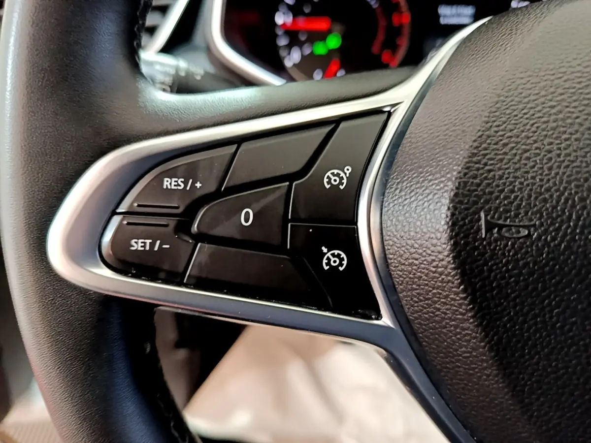 Gros plan sur les commandes de régulateur de vitesse au volant cuir noir de la Renault Clio Business 2020.