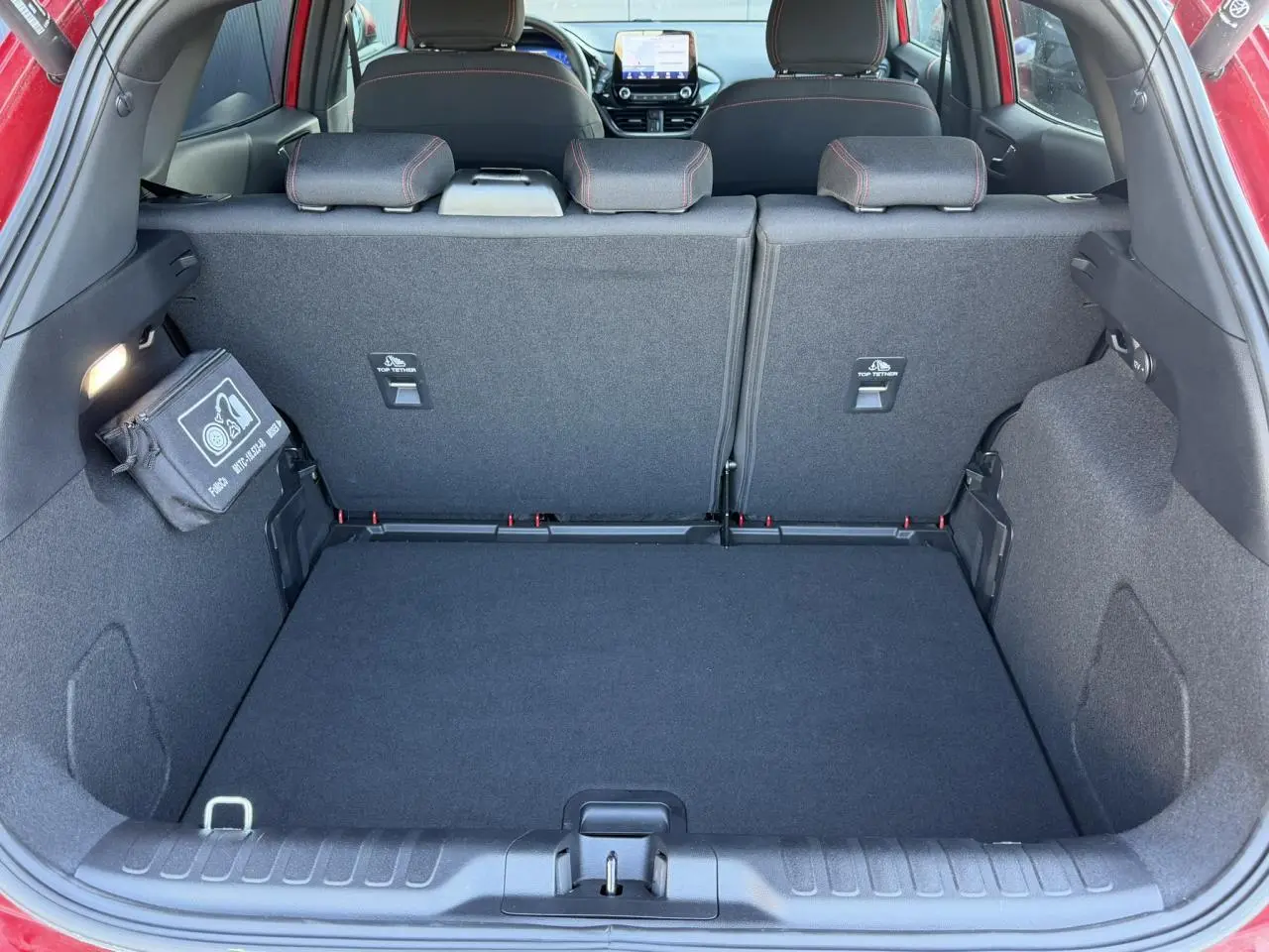 Vue intérieure du coffre ouvert d’un Ford Puma rouge Fantastic 2023, montrant les sièges arrière et la console centrale.