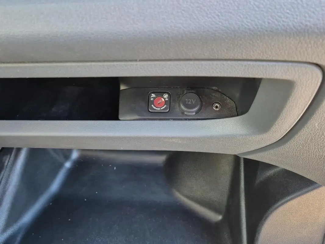 Détail de la console centrale du Citroën Jumpy blanc 2019 montrant une prise 12V et un interrupteur rouge.