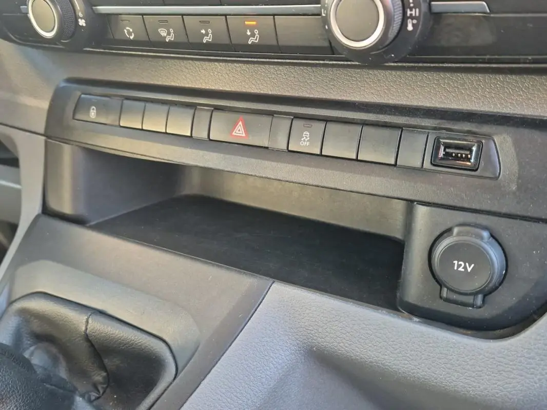 Détail de la console centrale du Citroën Jumpy blanc 2019, montrant les boutons de commande et prise 12V.