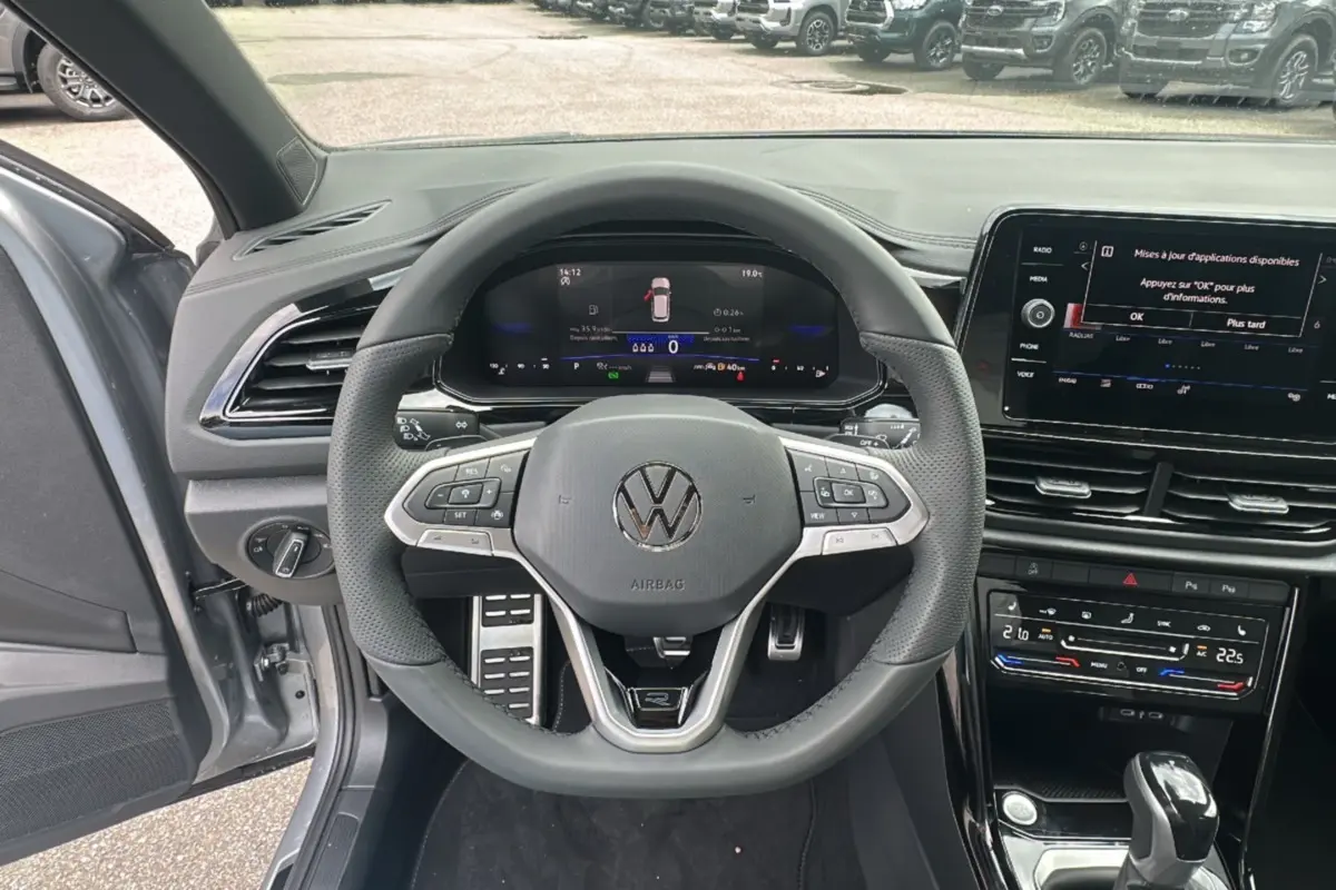 Vue intérieure centrée sur le volant multifonctions cuir du Volkswagen T-Roc gris pyrite avec tableau de bord digital.