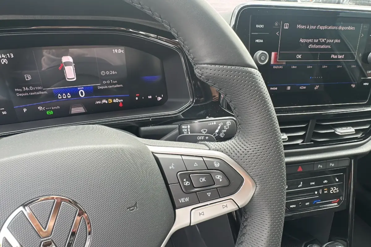 Vue rapprochée du volant cuir multifonctions et du tableau de bord digital du Volkswagen T-Roc gris pyrite 2025.