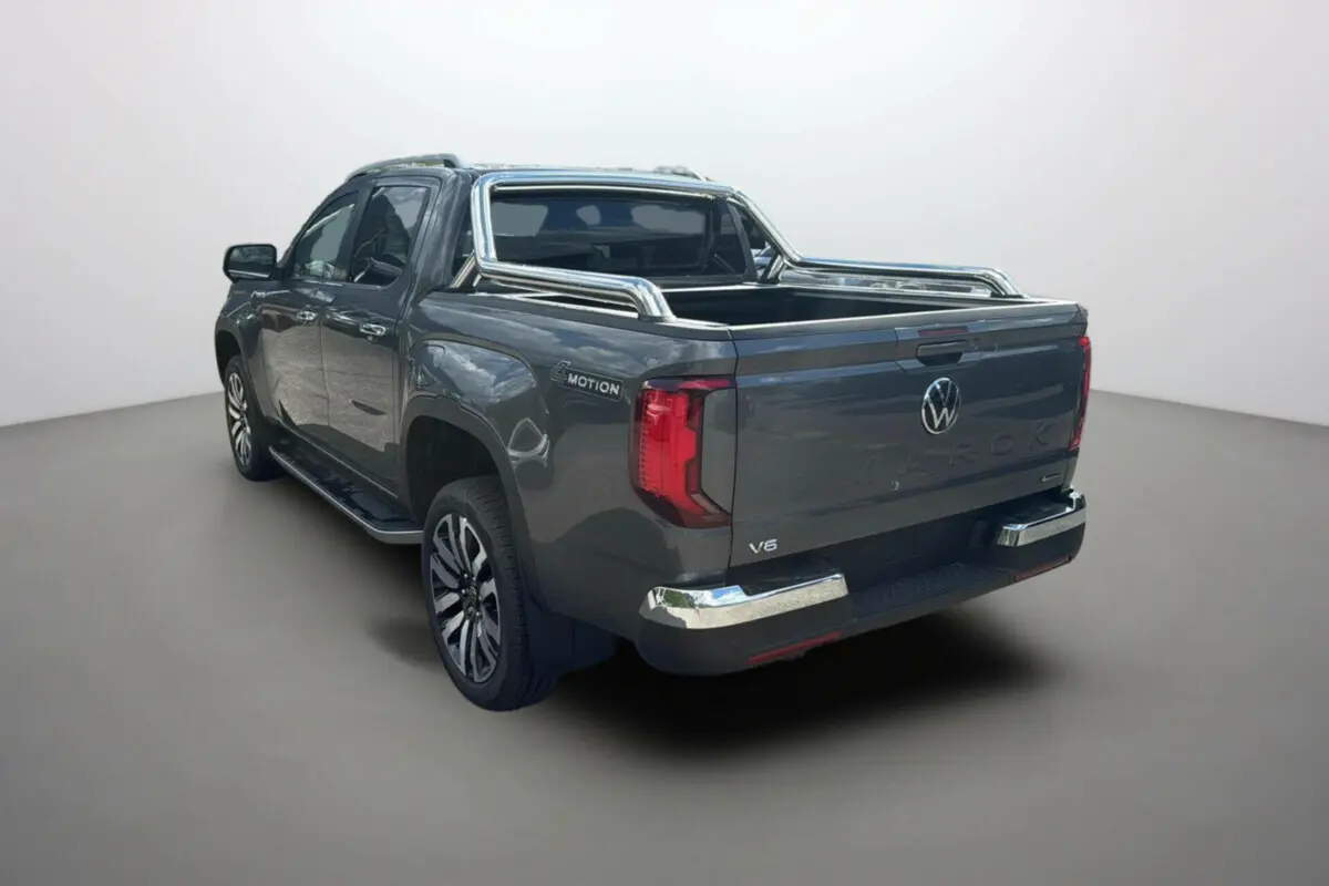 Vue 3/4 arrière droite du Volkswagen Amarok V6 240 BVA10 Aventura gris foncé avec arceaux inox et jantes alu.