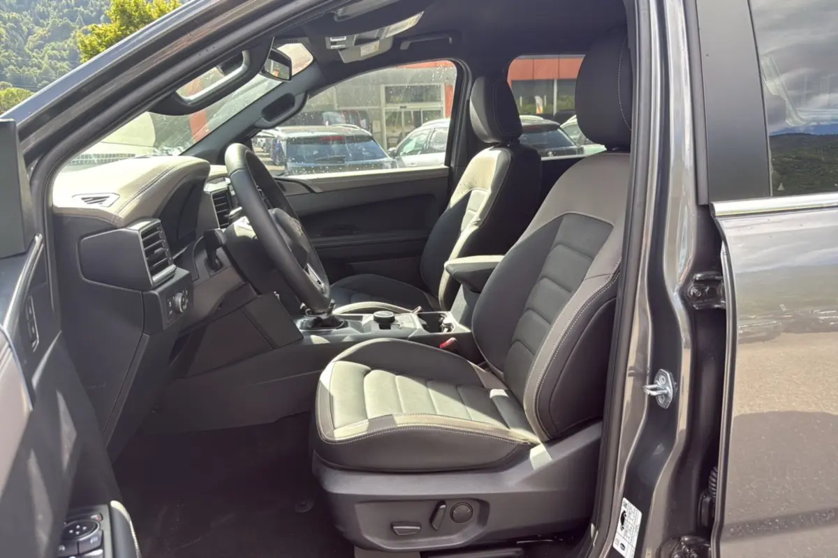 Vue intérieure côté conducteur du Volkswagen Amarok Simple Cabine V6 240 BVA10 Aventura 2026 en gris foncé avec sièges cuir noirs.