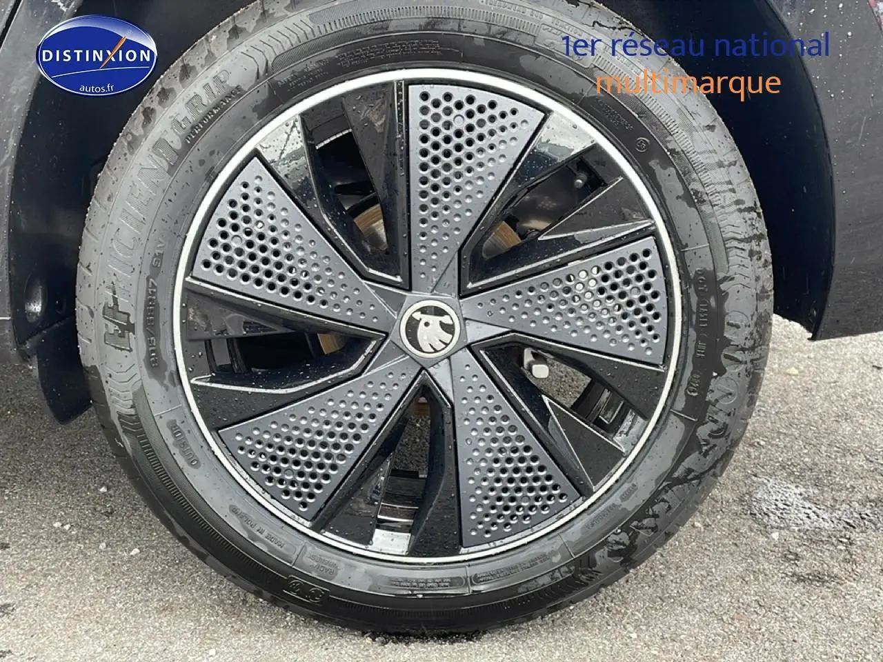 Gros plan sur la jante alu noire et grise au design perforé d'un Skoda Kamiq noir, côté droit.