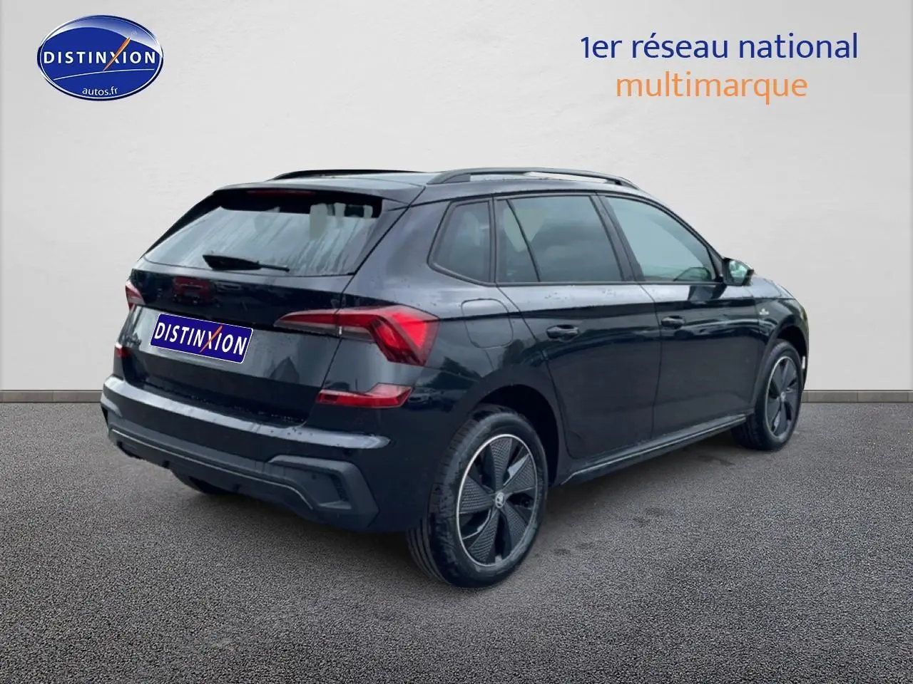 Vue 3/4 arrière droite d'un Skoda Kamiq noir avec jantes alu et barres de toit visibles sur fond neutre.