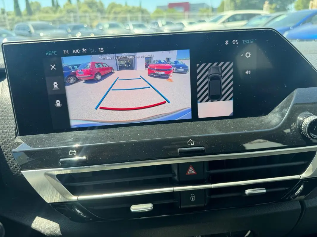 Écran central de la Citroën C4 hybride blanc montrant la caméra de recul avec vue arrière et capteurs de stationnement.