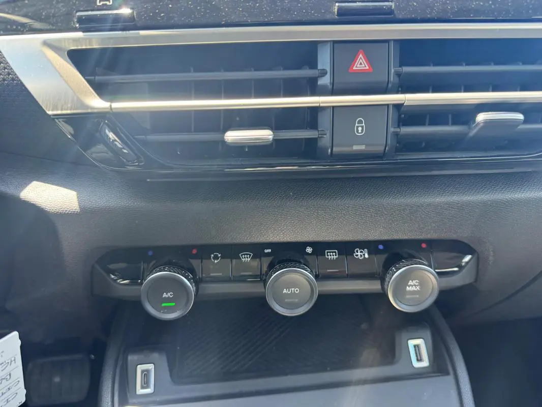 Vue rapprochée du tableau de bord de la Citroën C4 hybride blanc, montrant les commandes de climatisation automatique.