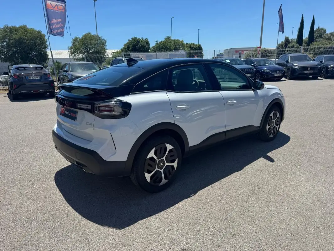 Citroën C4 hybride blanc vue 3/4 arrière droit, toit noir, jantes alliage 18 pouces et feux arrière distinctifs.
