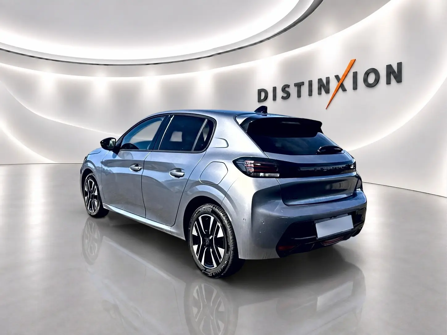 Peugeot 208 gris artense vue 3/4 arrière droit dans un showroom lumineux avec jantes alu noires.