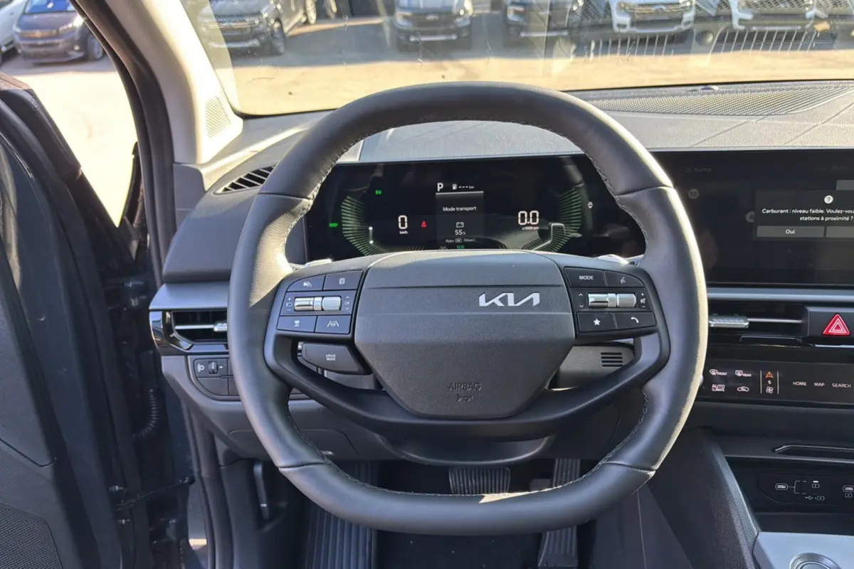 Vue centrée sur le volant cuir multifonctions du Kia Sportage gris eclipse avec tableau de bord numérique et écran tactile.