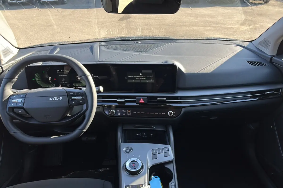 Intérieur avant du Kia Sportage gris eclipse 2026, tableau de bord moderne avec écran large et volant multifonctions cuir.