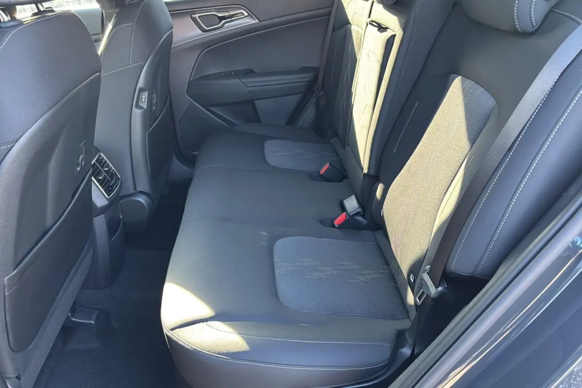 Vue côté droit de la banquette arrière en tissu gris du Kia Sportage 2026, avec ceinture de sécurité et porte arrière ouverte.