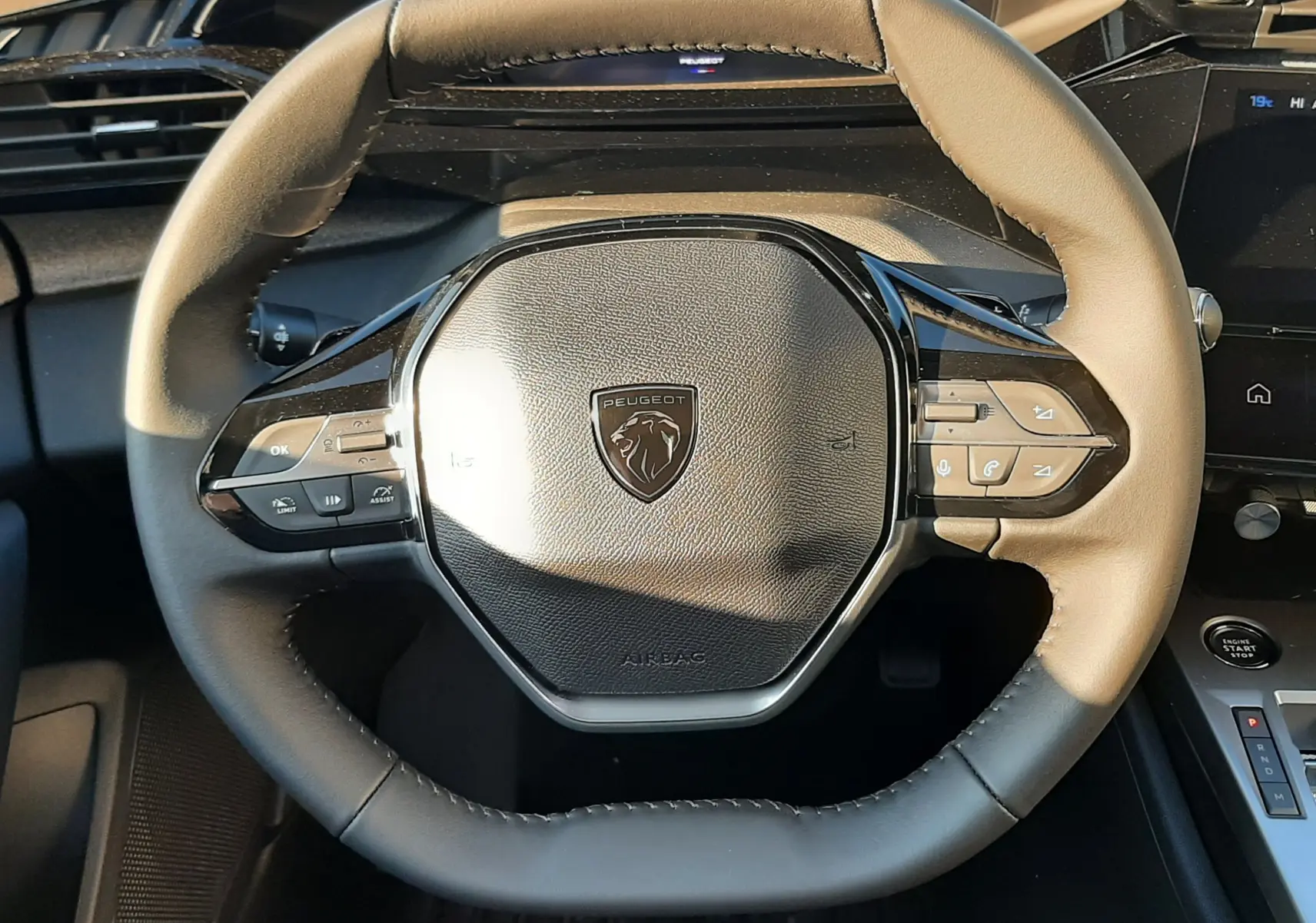 Vue rapprochée du volant cuir bicolore avec logo Peugeot du tableau de bord intérieur d'une 308 Bleu Obsession 2025