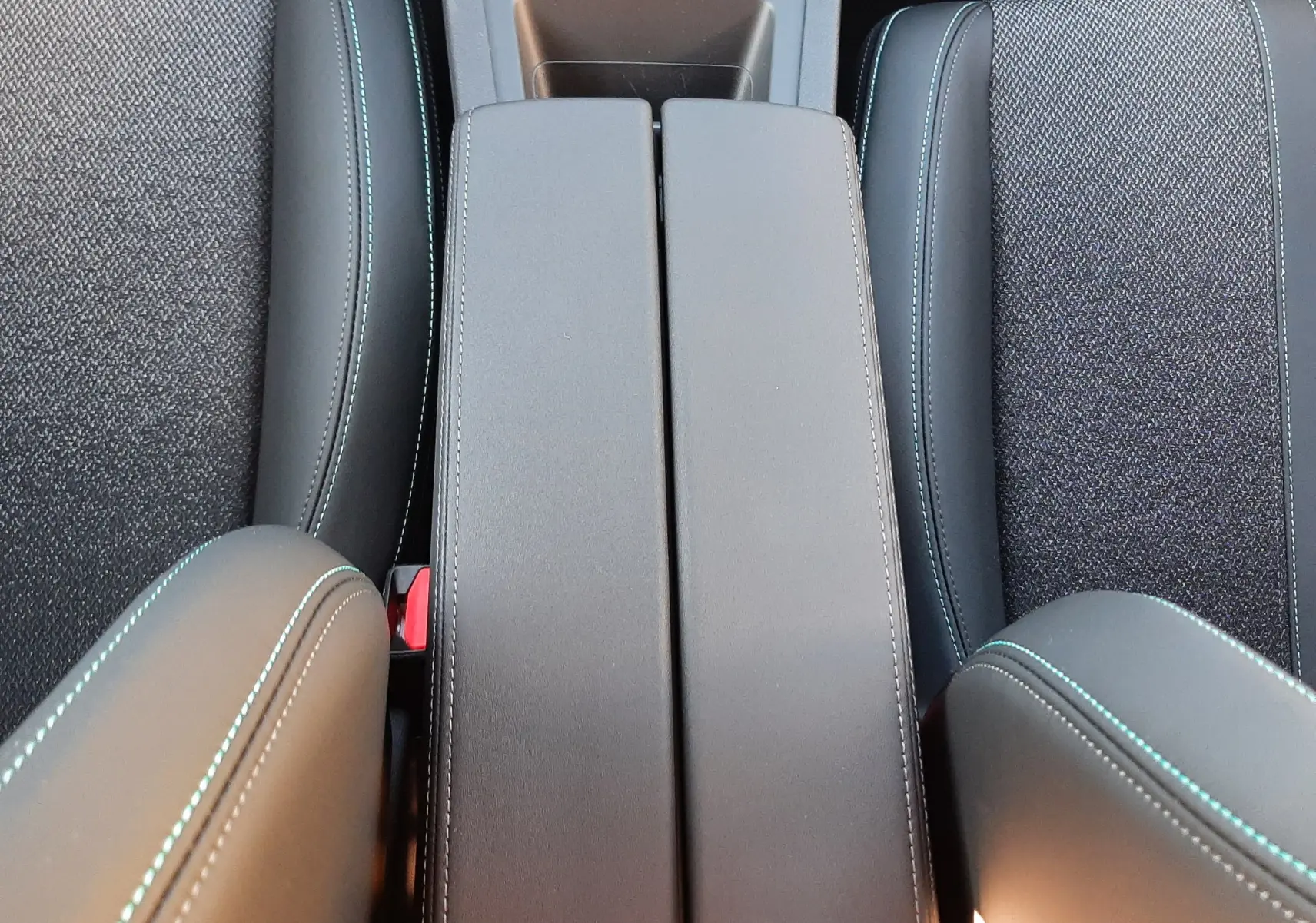 Vue plongeante sur la console centrale et les sièges avant noirs avec surpiqûres bleues du Peugeot 308 Bleu Obsession 2025.