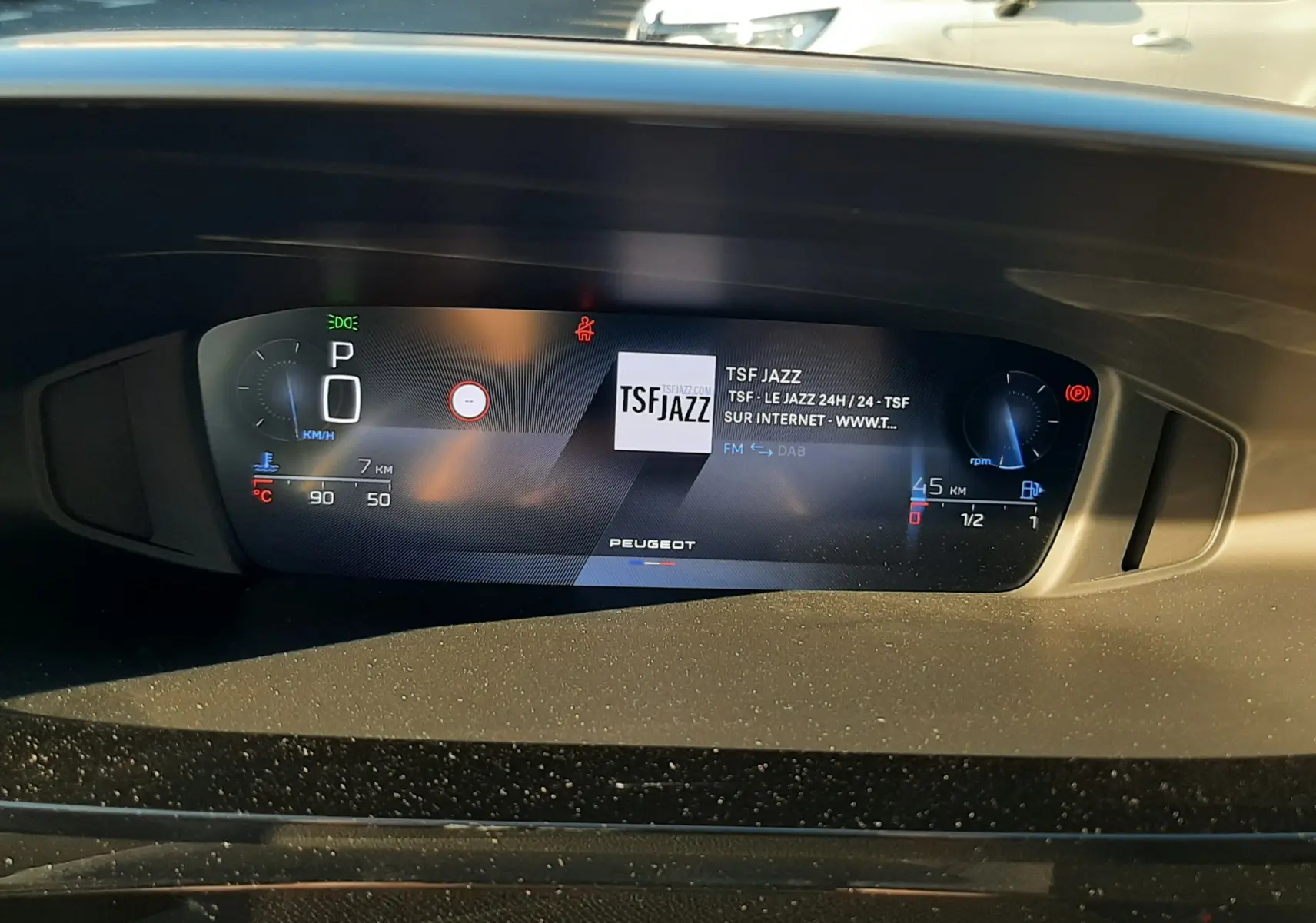 Tableau de bord numérique du Peugeot 308 Bleu Obsession 2025 affichant la radio TSF Jazz et les indicateurs de vitesse et carburant.
