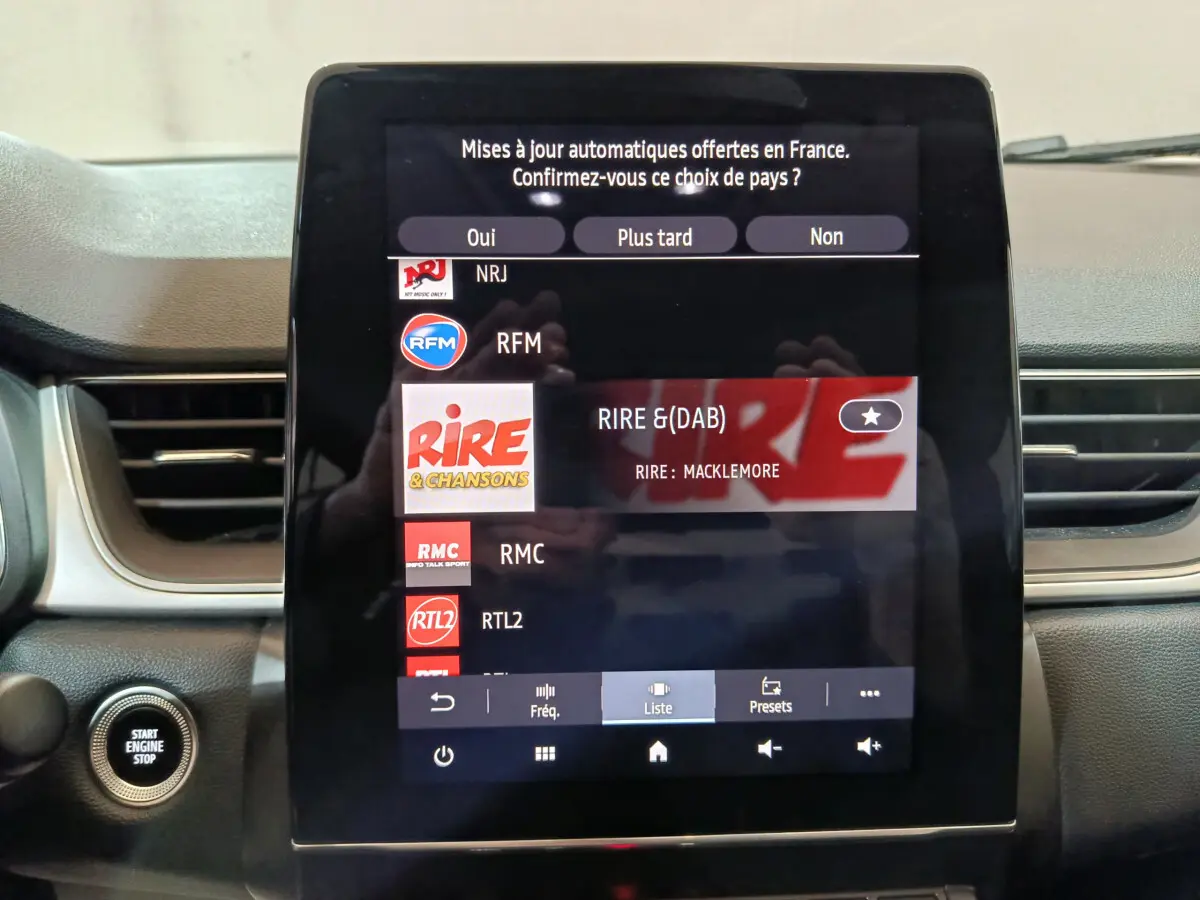 Écran tactile central du tableau de bord du Renault Captur rouge 2024 affichant les stations radio numériques.