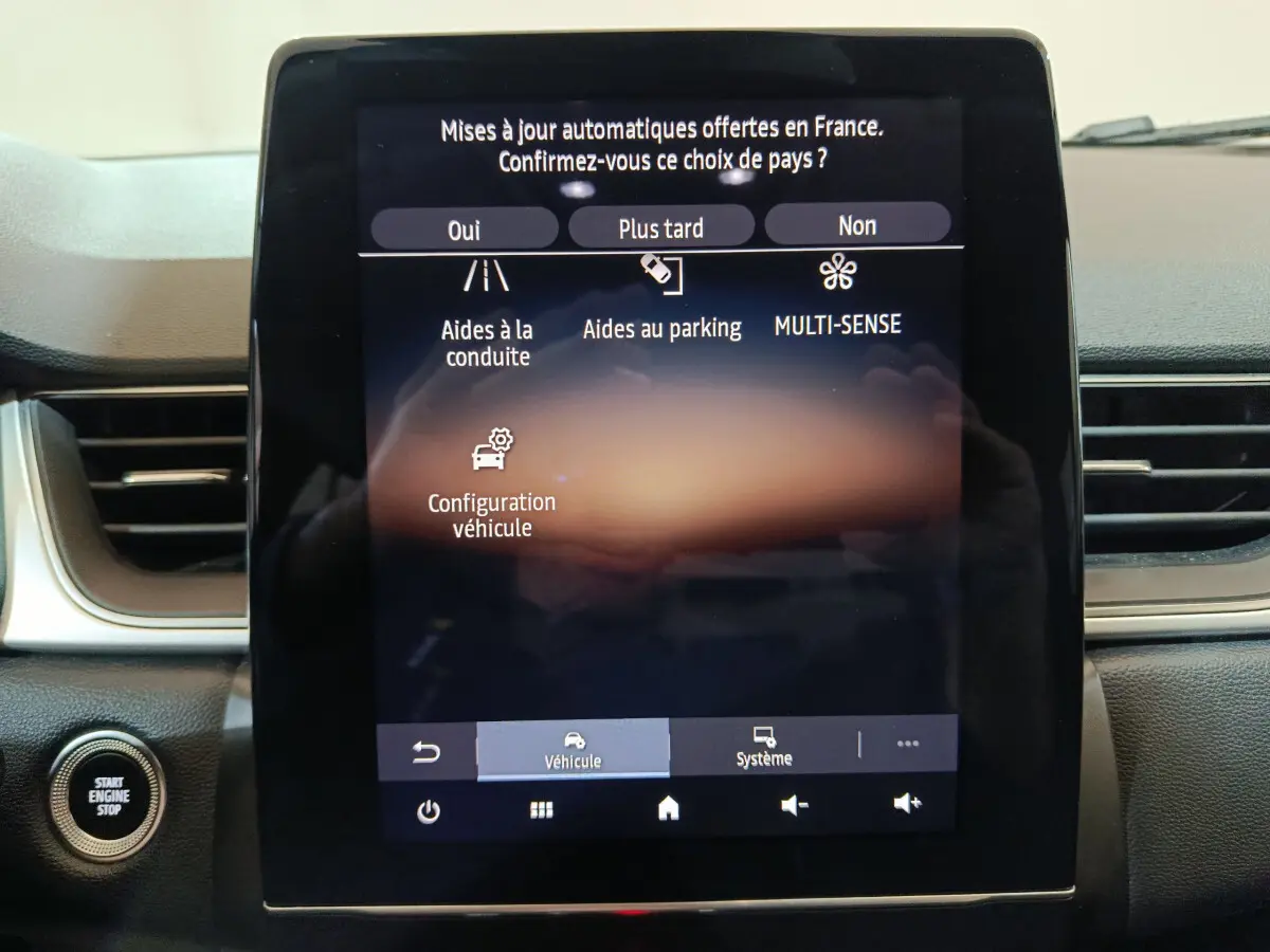 Écran tactile central du tableau de bord du Renault Captur rouge 2024 affichant les options d'aide à la conduite et configuration véhicule.