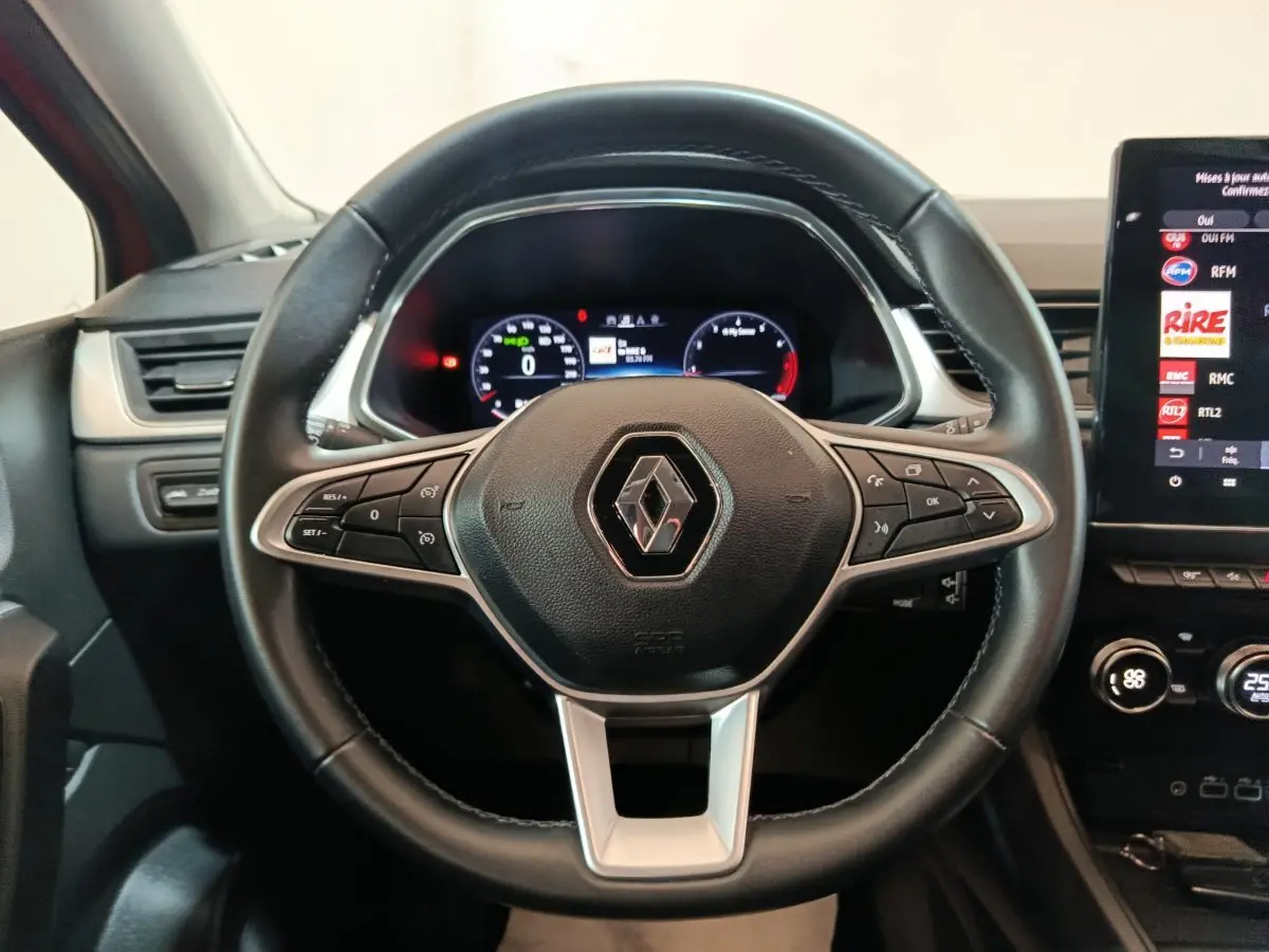 Volant noir Renault Captur 2024 avec commandes intégrées et tableau de bord numérique en arrière-plan.