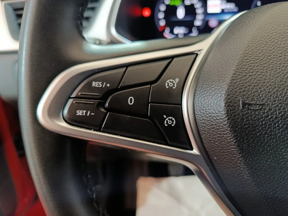Gros plan sur les commandes du régulateur de vitesse au volant du Renault Captur rouge 2024.