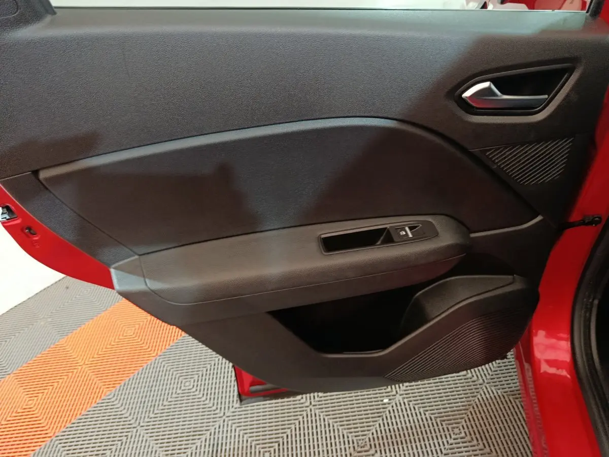 Porte intérieure côté gauche noire du Renault Captur rouge 2024, avec poignée argentée et commande de vitre électrique.