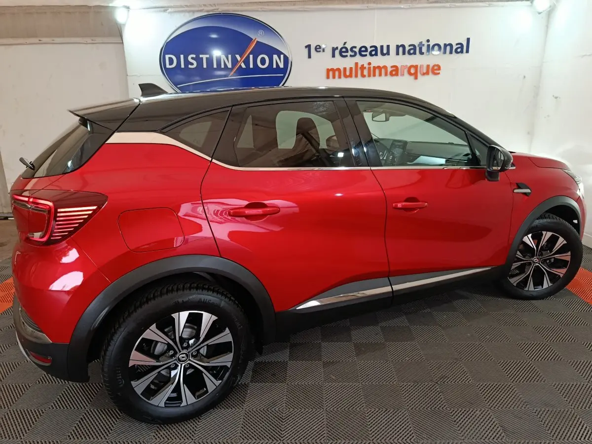 Profil côté gauche d'un Renault Captur Techno TCe 90 rouge 2024 avec toit noir et jantes alliage bicolores.