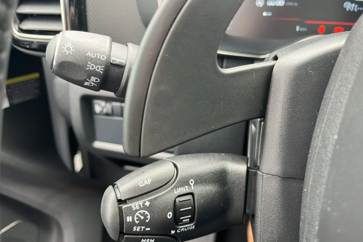 Gros plan sur les commandes au volant noir du Citroën C5 Aircross blanc, avec palettes et régulateur de vitesse.