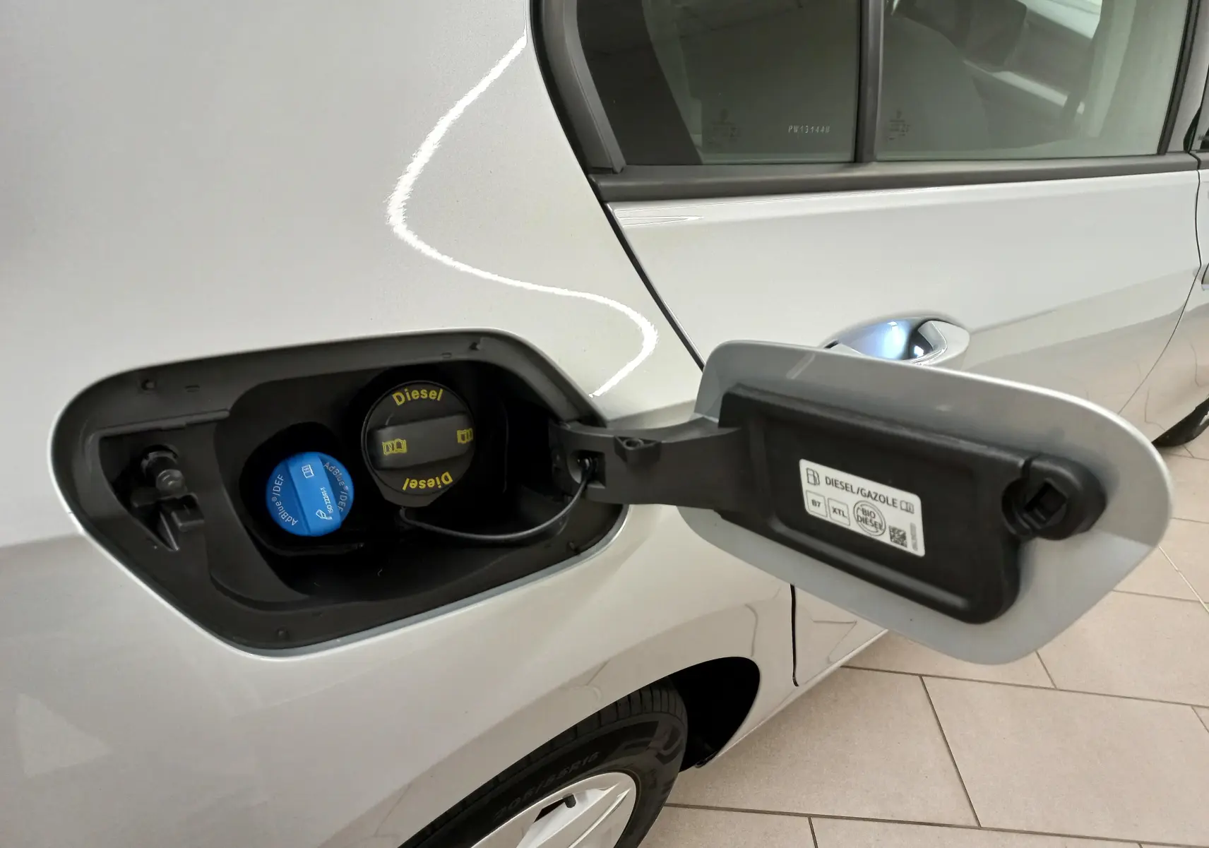 Vue rapprochée de la trappe à carburant côté gauche d'une Volkswagen Golf 2.0 TDI argentée avec bouchons Diesel et AdBlue visibles.