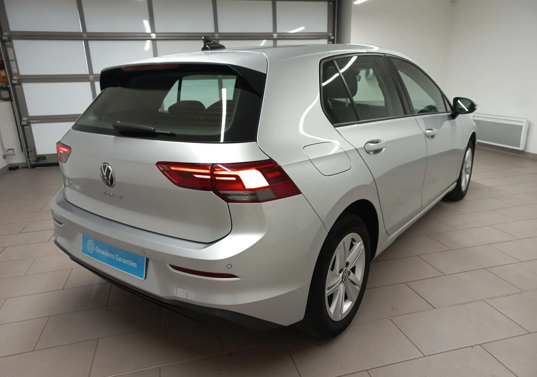 Vue 3/4 arrière droite d'une Volkswagen Golf 2.0 TDI 116 DSG7 Life Plus 2023 en reflet d'argent dans un garage.