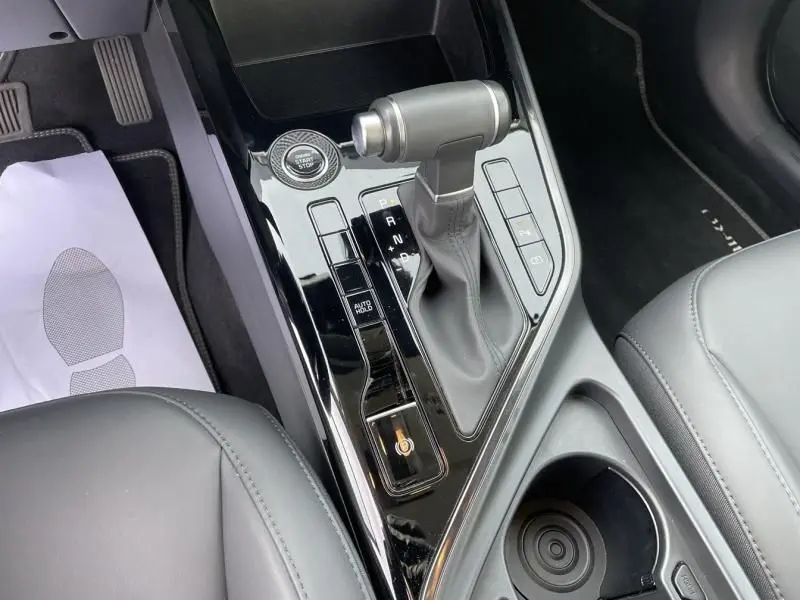 Vue rapprochée de la console centrale du Kia Niro 2024 bleu métal, avec levier de vitesse automatique et bouton start/stop.