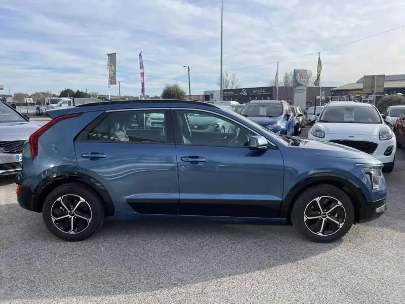 Vue de profil côté gauche du KIA Niro 2024 bleu métal, soulignant ses jantes alliage et ses lignes modernes.