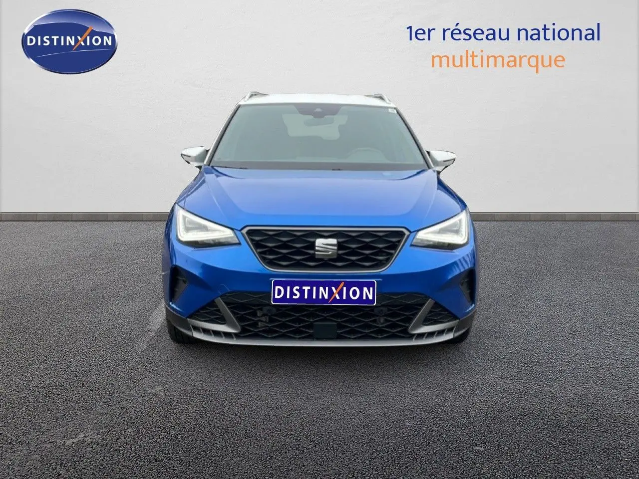 Vue avant d'un SEAT Arona bleu saphir métal avec toit blanc, calandre noire et phares LED allumés.