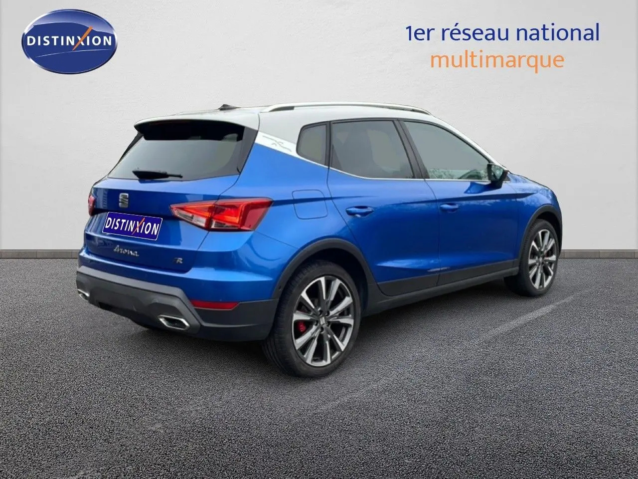 Vue 3/4 arrière droite d’un SEAT Arona bleu saphir métal avec toit blanc, jantes alliage et feux arrière LED.