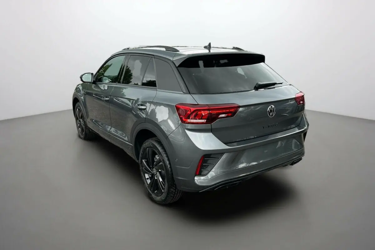 Vue 3/4 arrière du Volkswagen T-Roc gris indium avec jantes noires et vitres surteintées dans un studio.