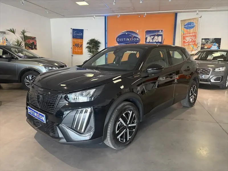 Peugeot 2008 Hybrid 145ch noir métal en 3/4 avant droit dans un showroom avec logo Distinxion visible.