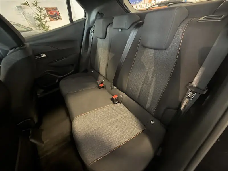 Vue intérieure arrière du Peugeot 2008 Hybrid 145ch Style 2025, sièges tissu noir et gris avec surpiqûres orange.