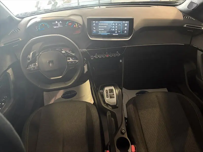 Vue intérieure avant du Peugeot 2008 Hybrid 145ch Style 2025, tableau de bord noir avec écran tactile et volant compact.