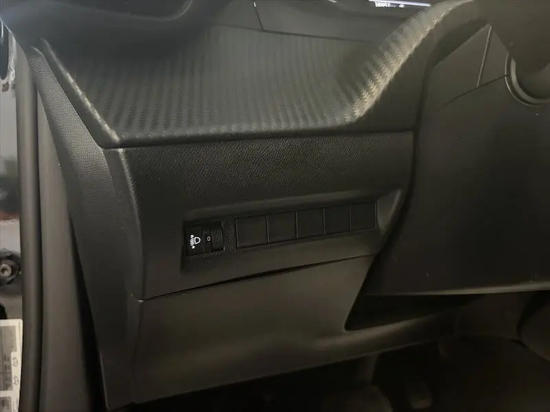 Détail intérieur montrant la console côté gauche avec commande de réglage des phares sur Peugeot 2008 noir métal 2025.
