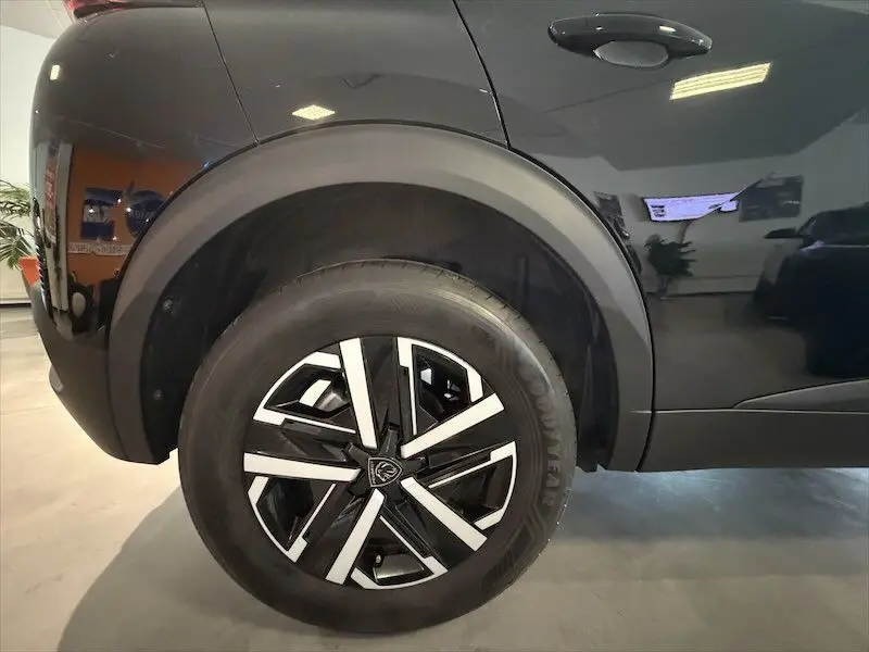Gros plan sur la roue arrière droite noire métallisée du Peugeot 2008 Hybrid 145ch avec jante alliage bicolore.