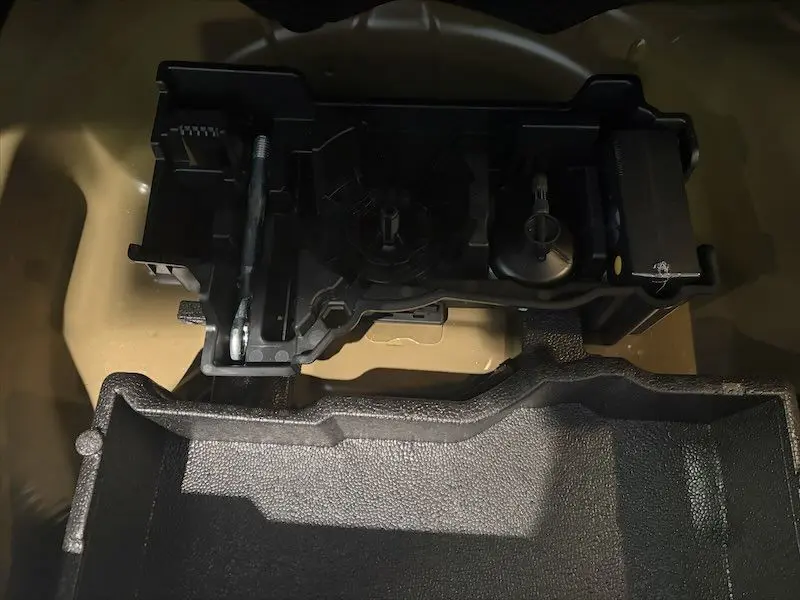 Gros plan sur le rangement intérieur du coffre d’un Peugeot 2008 noir métal, montrant un support en plastique noir.