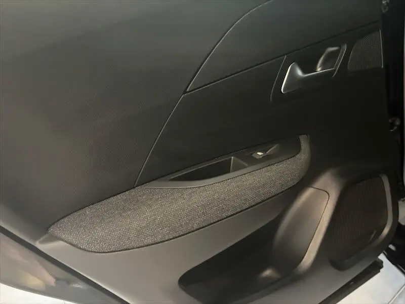 Gros plan sur la porte intérieure côté gauche du Peugeot 2008 noir métal, avec tissu gris et commande de fenêtre.