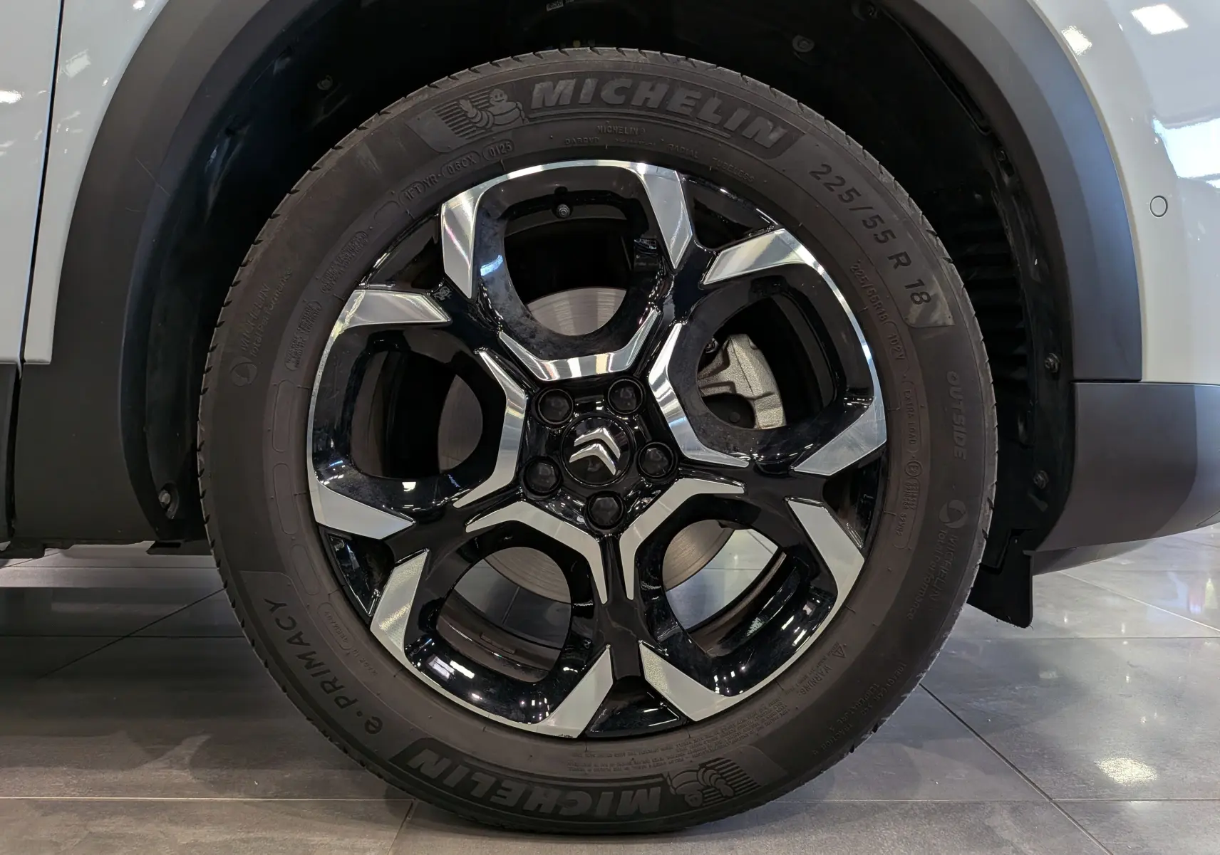 Gros plan sur la roue avant droite du Citroën C5 Aircross 2025 blanc Okénite avec jante alliage noire et argentée.