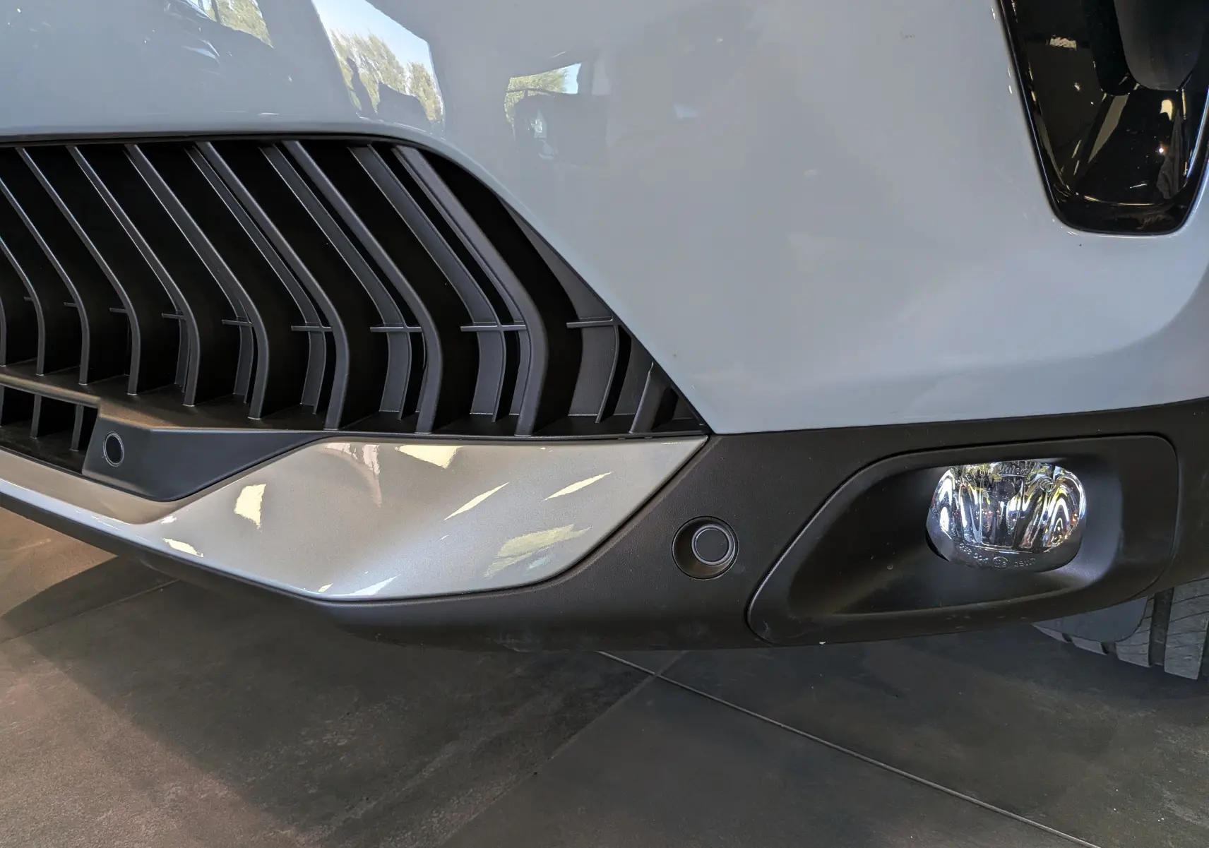 Gros plan sur le pare-chocs avant blanc Okénite du Citroën C5 Aircross 2025 avec antibrouillard et grille noire.