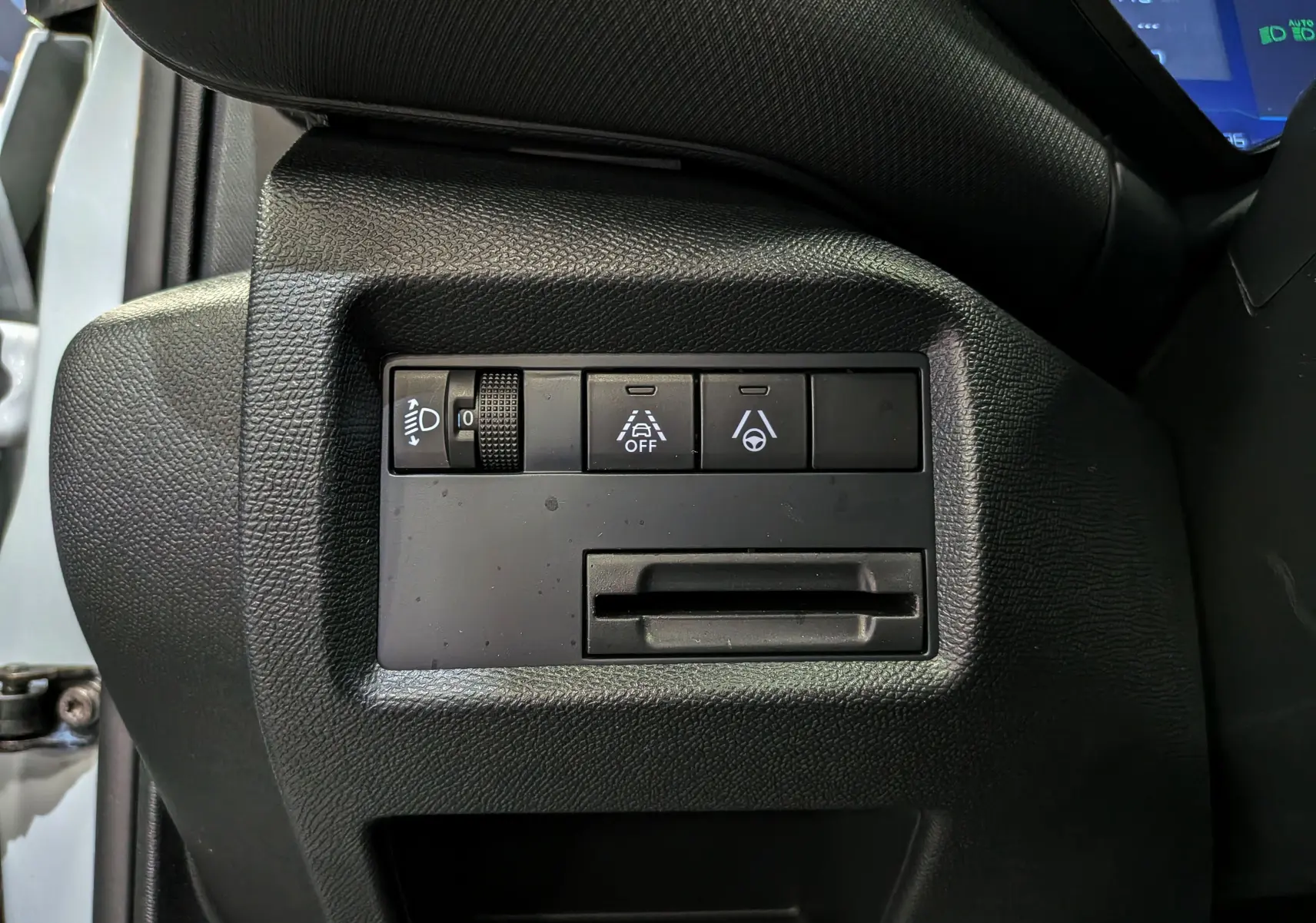 Vue rapprochée des commandes de réglage d’éclairage et d’aide à la conduite sur le côté gauche du tableau de bord d’un Citroën C5 Aircross blanc.