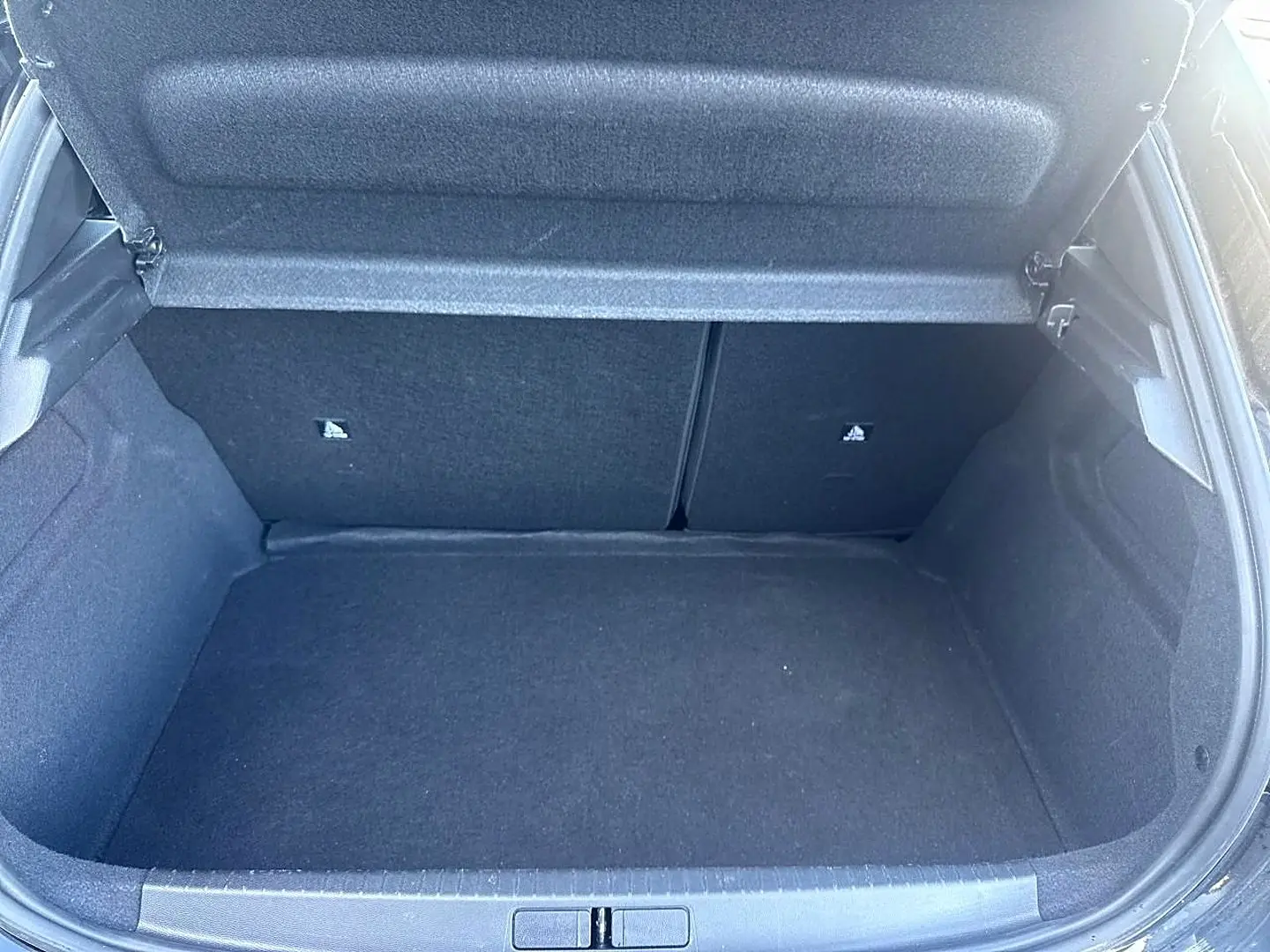 Coffre ouvert de la Peugeot 208 1.2 100 Allure noir, vue intérieure montrant l'espace de rangement vide.