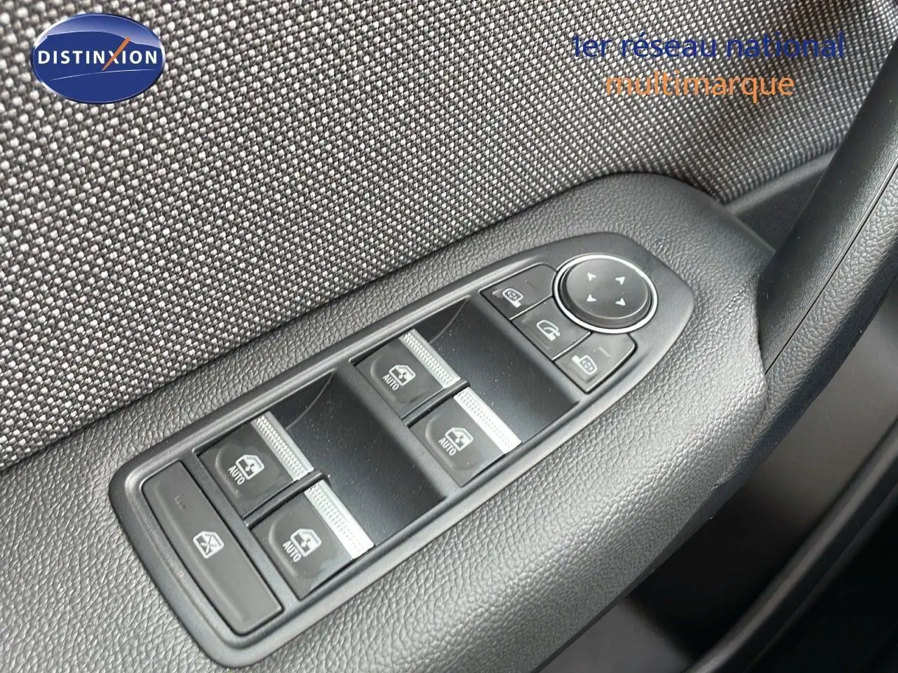 Gros plan sur les commandes des vitres électriques côté conducteur d'une Renault Captur 2025, finition tissu gris.