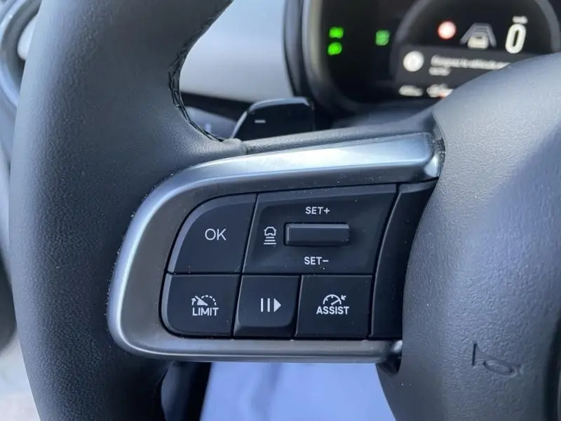 Gros plan sur les commandes au volant côté gauche du Fiat 600 blanc 2025, avec boutons de régulateur et assistant de conduite.