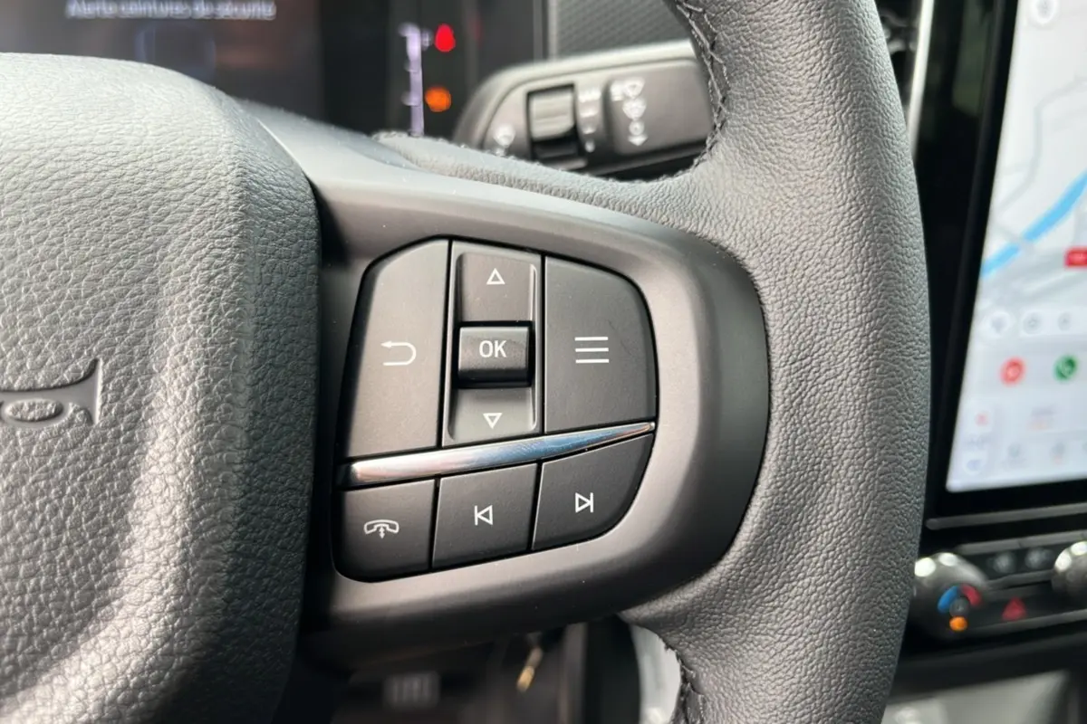 Gros plan sur les commandes multifonctions à droite du volant cuir noir du Ford Ranger gris carbone, avec écran tactile visible.