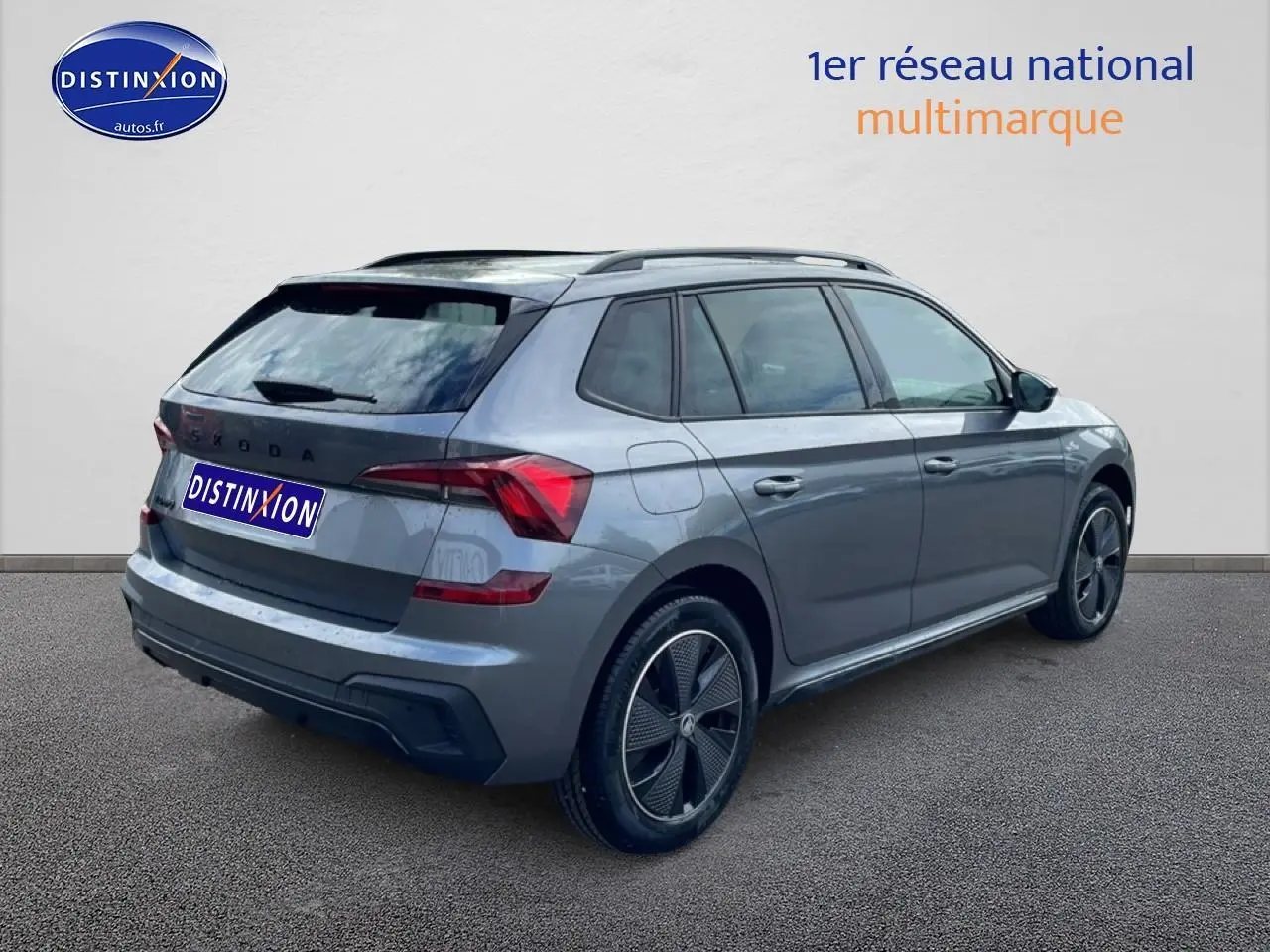 Vue 3/4 arrière droite d’un Skoda Kamiq gris graphite avec jantes alu noires et toit panoramique en verre.