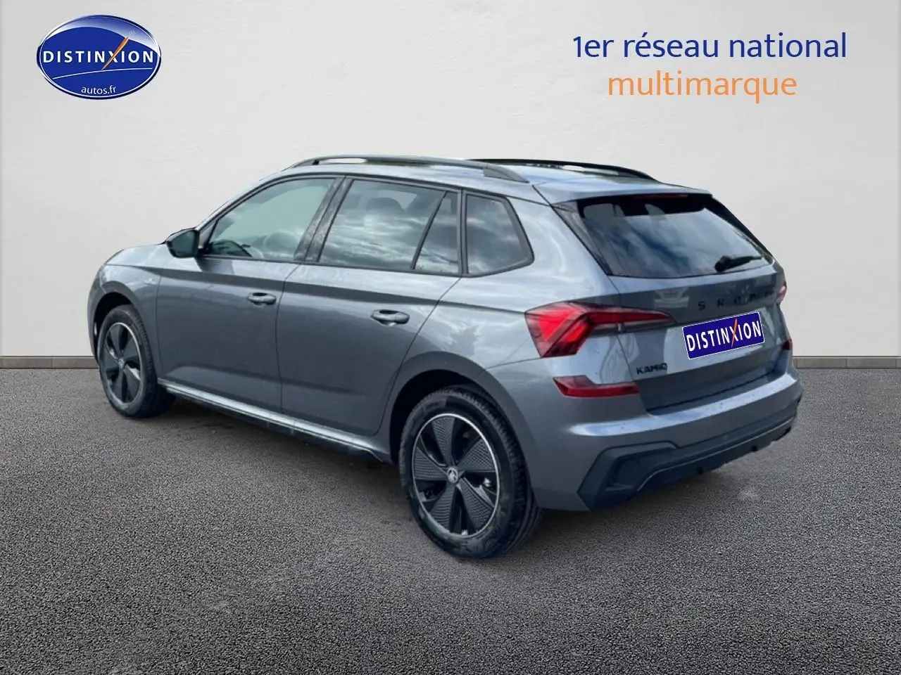 Vue 3/4 arrière droite d'un Skoda Kamiq gris graphite avec jantes alu noires et barres de toit.